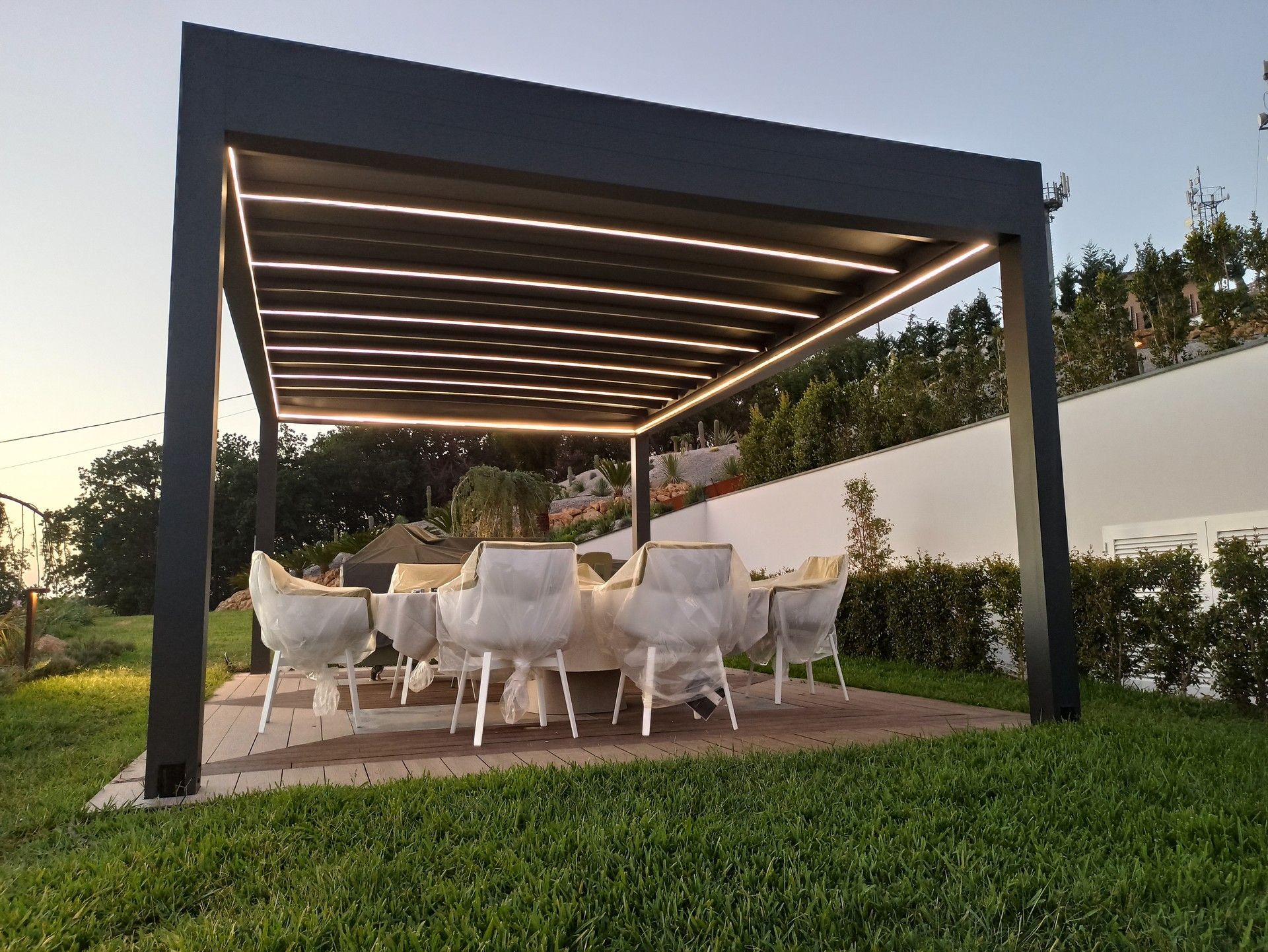 Un pergolato con tavolo e sedie sotto.