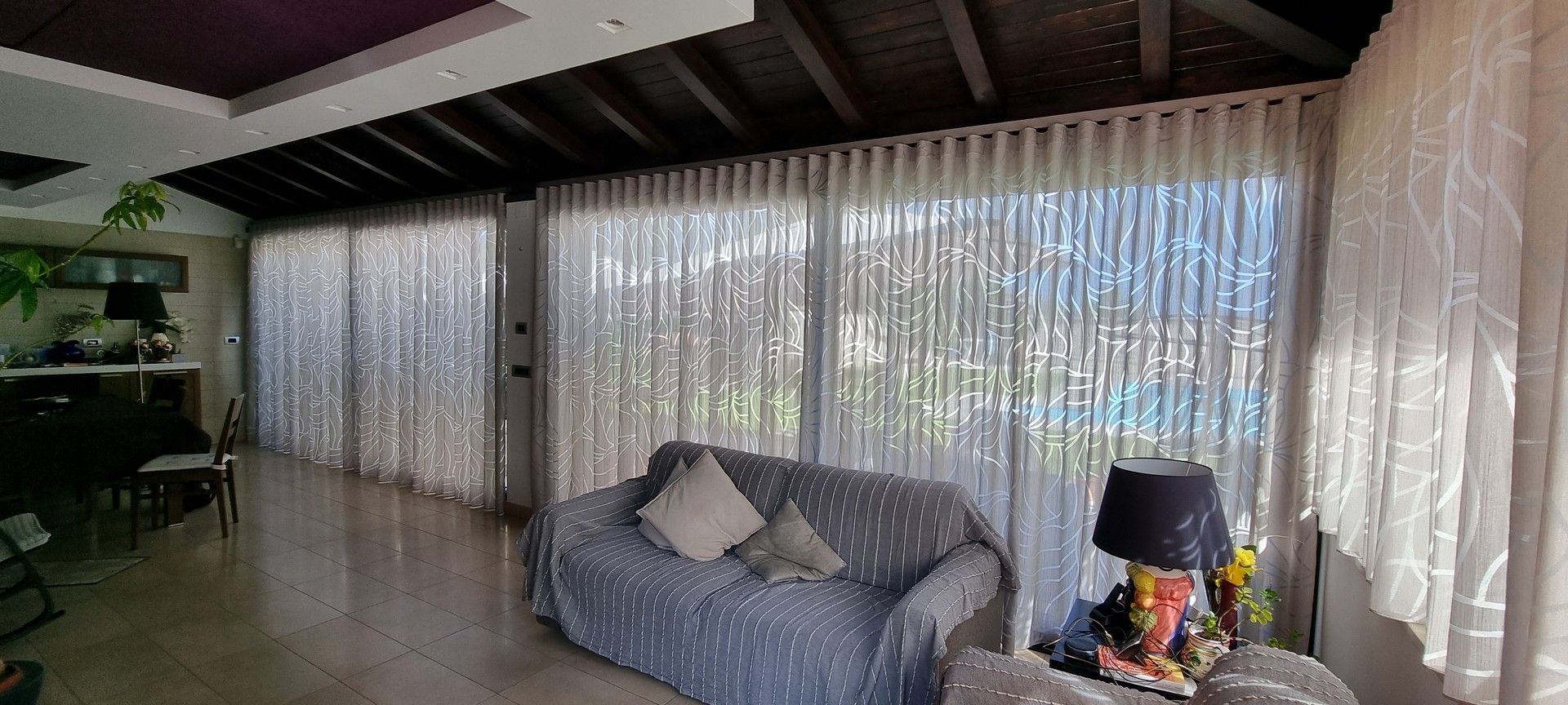 Un soggiorno con divano, tavolo, lampada e tende.