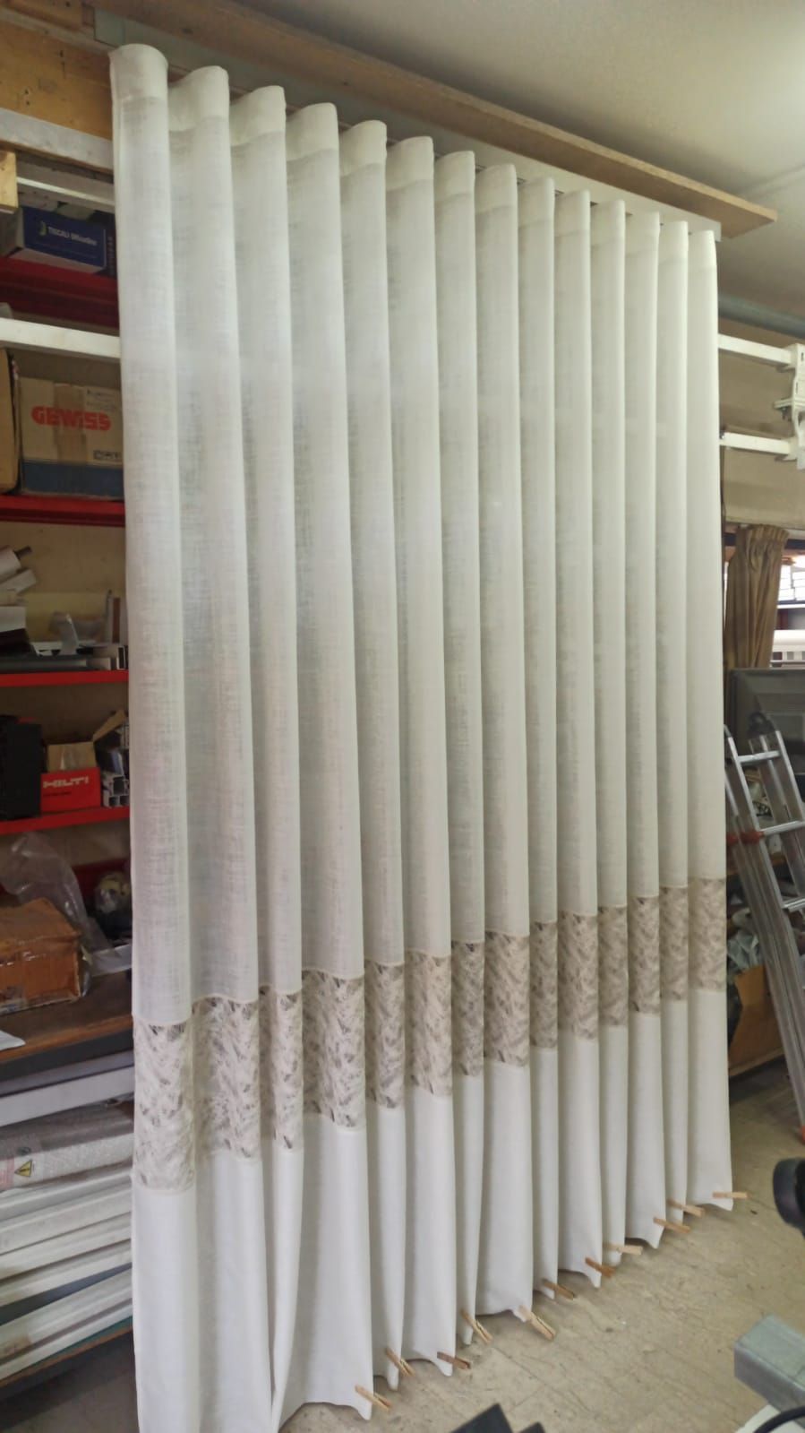 Una fila di tende bianche sono appese alla parete di una stanza.