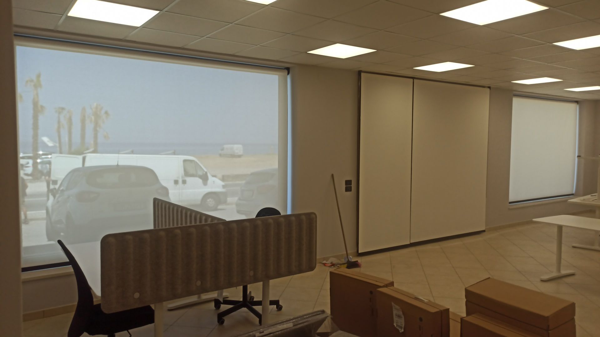 Una grande stanza con molte finestre e scatole sul pavimento.