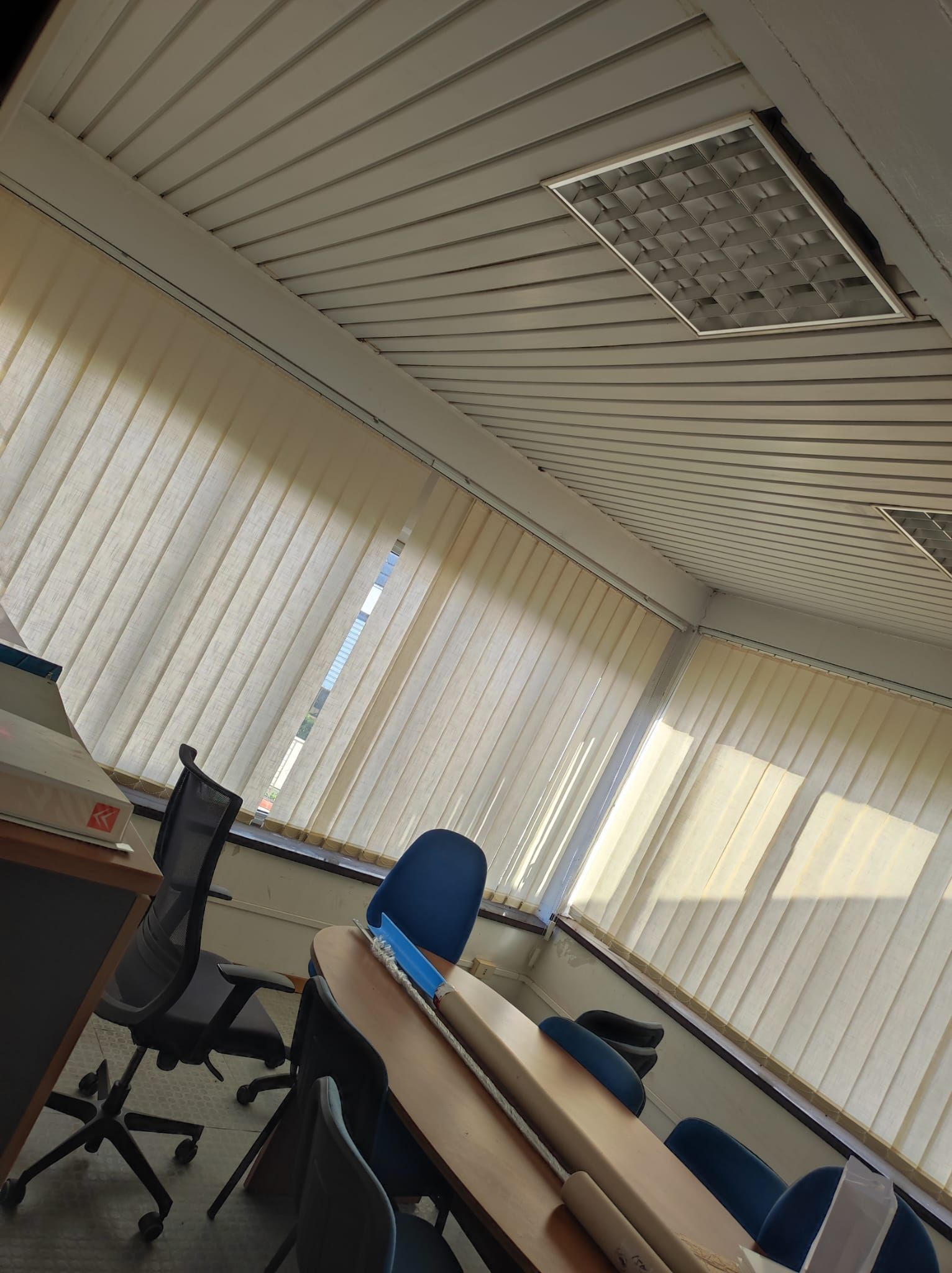 Una stanza con un tavolo e sedie e persiane alle finestre