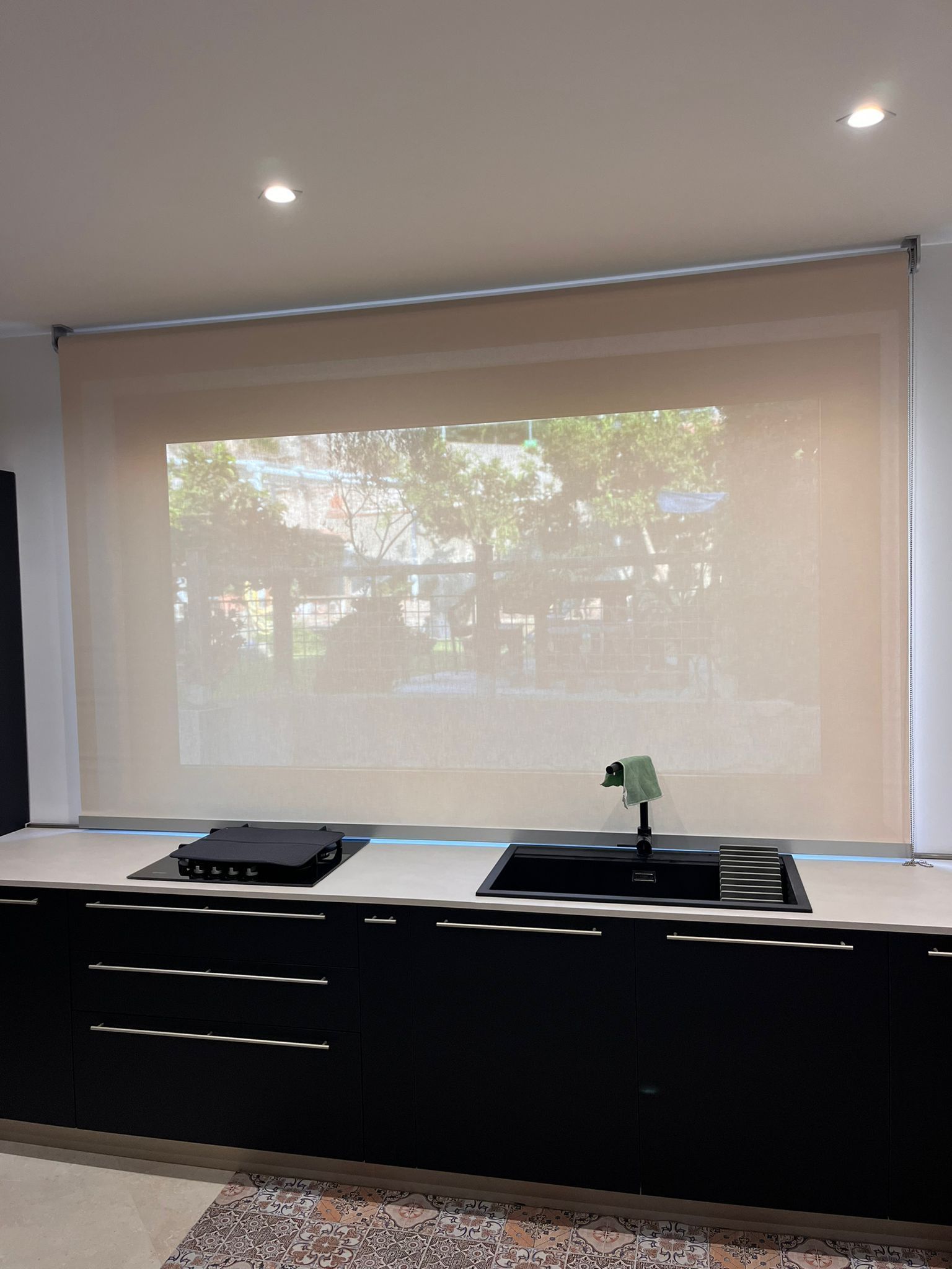 Una cucina con mobili neri e una grande finestra con una tenda.