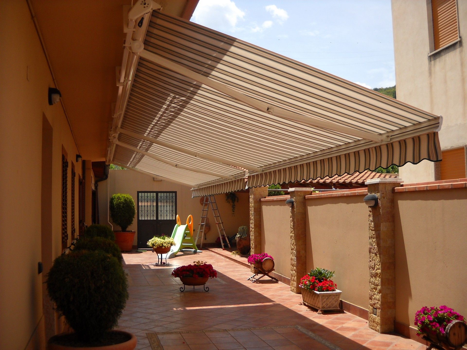 Un patio con una tenda a strisce sopra