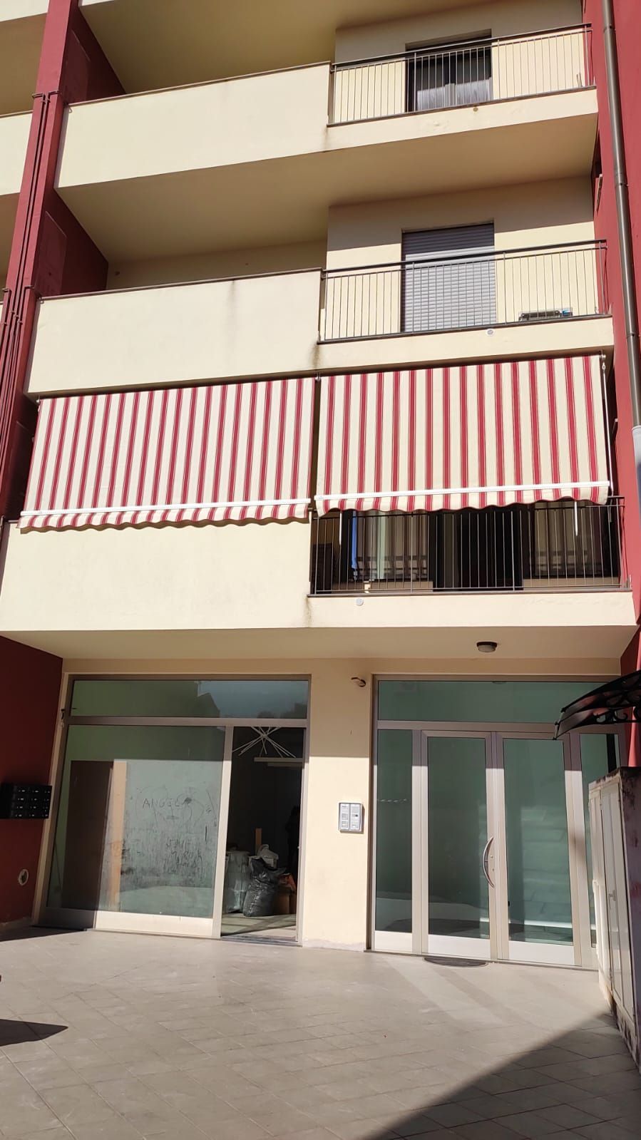 Un edificio con tende da sole a strisce rosse e bianche sui balconi