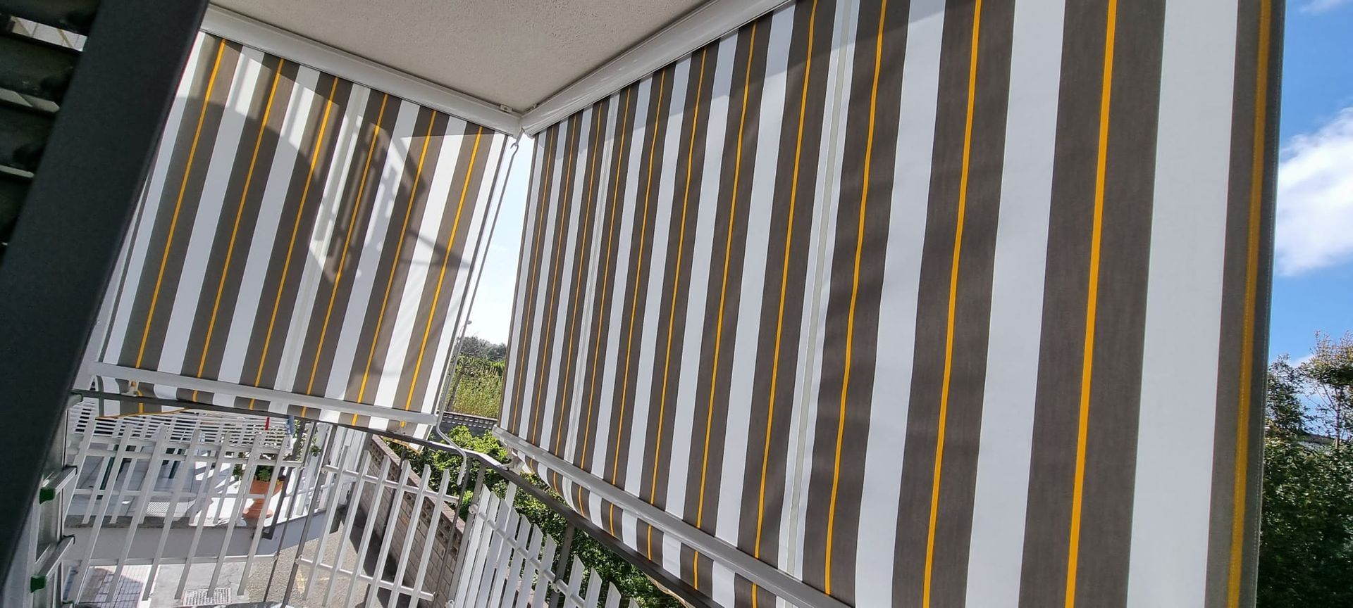 Un balcone con una tenda a strisce sul lato