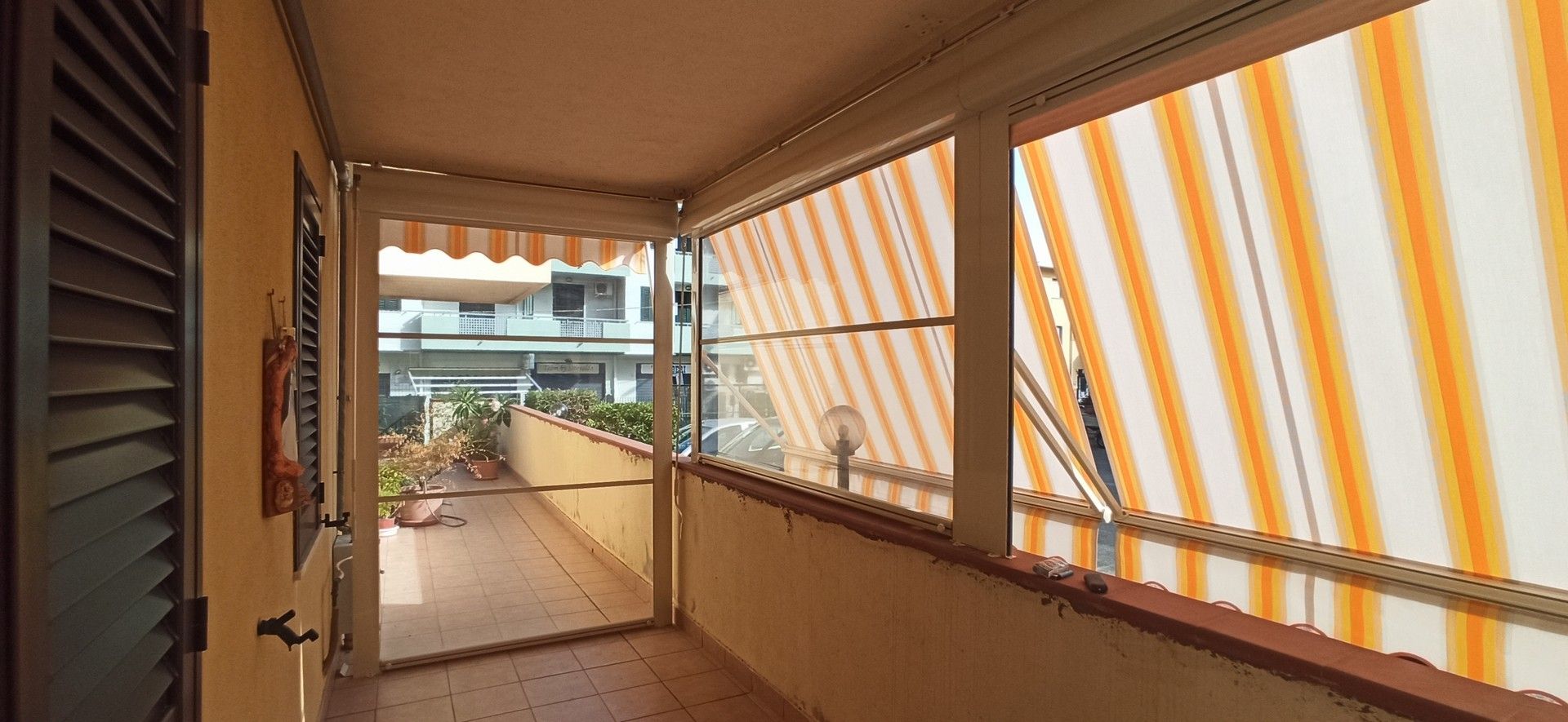Un balcone con tende da sole a strisce arancioni e bianche alle finestre.