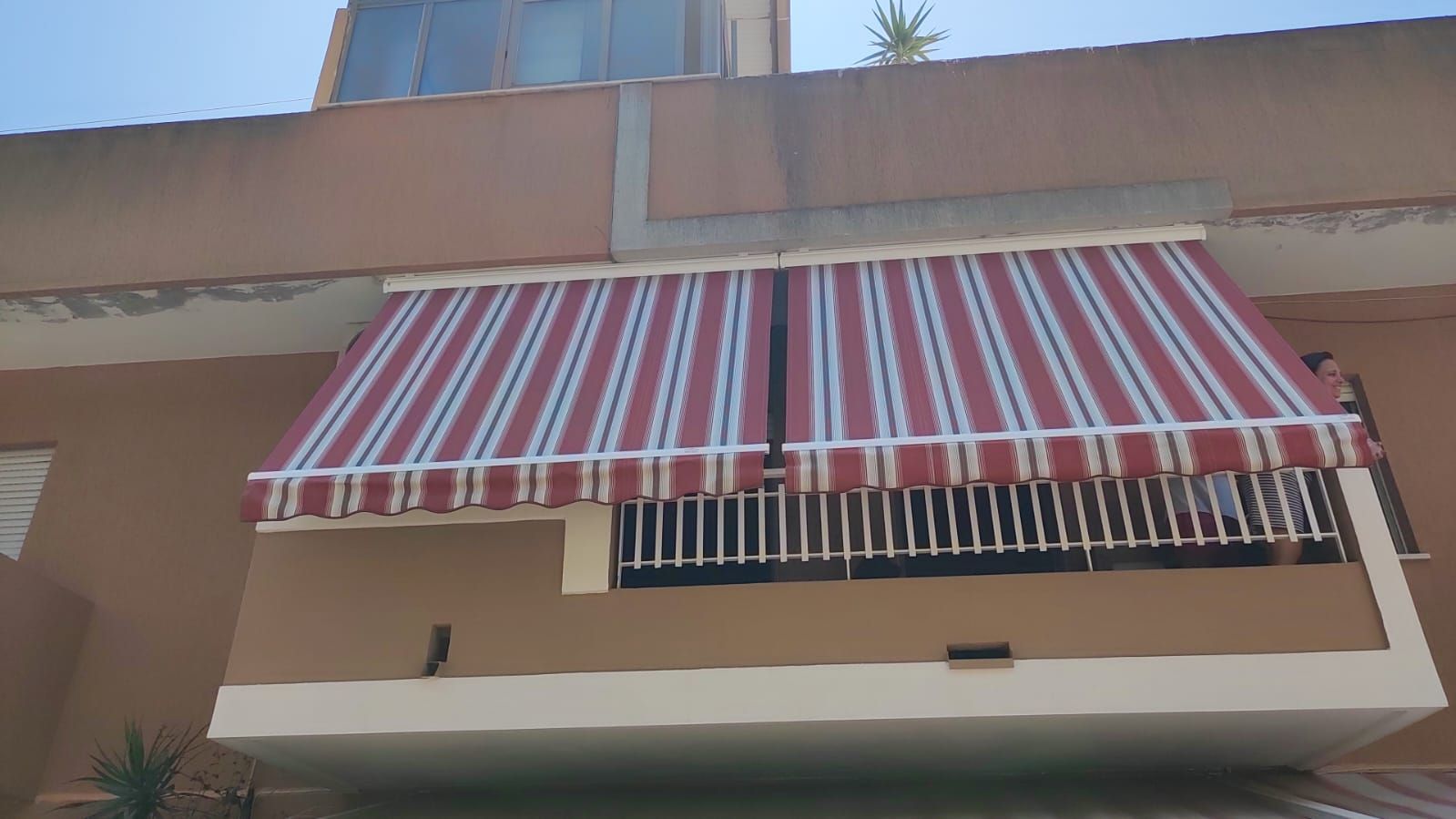 Una tenda da sole a strisce rosse e bianche è su un balcone.
