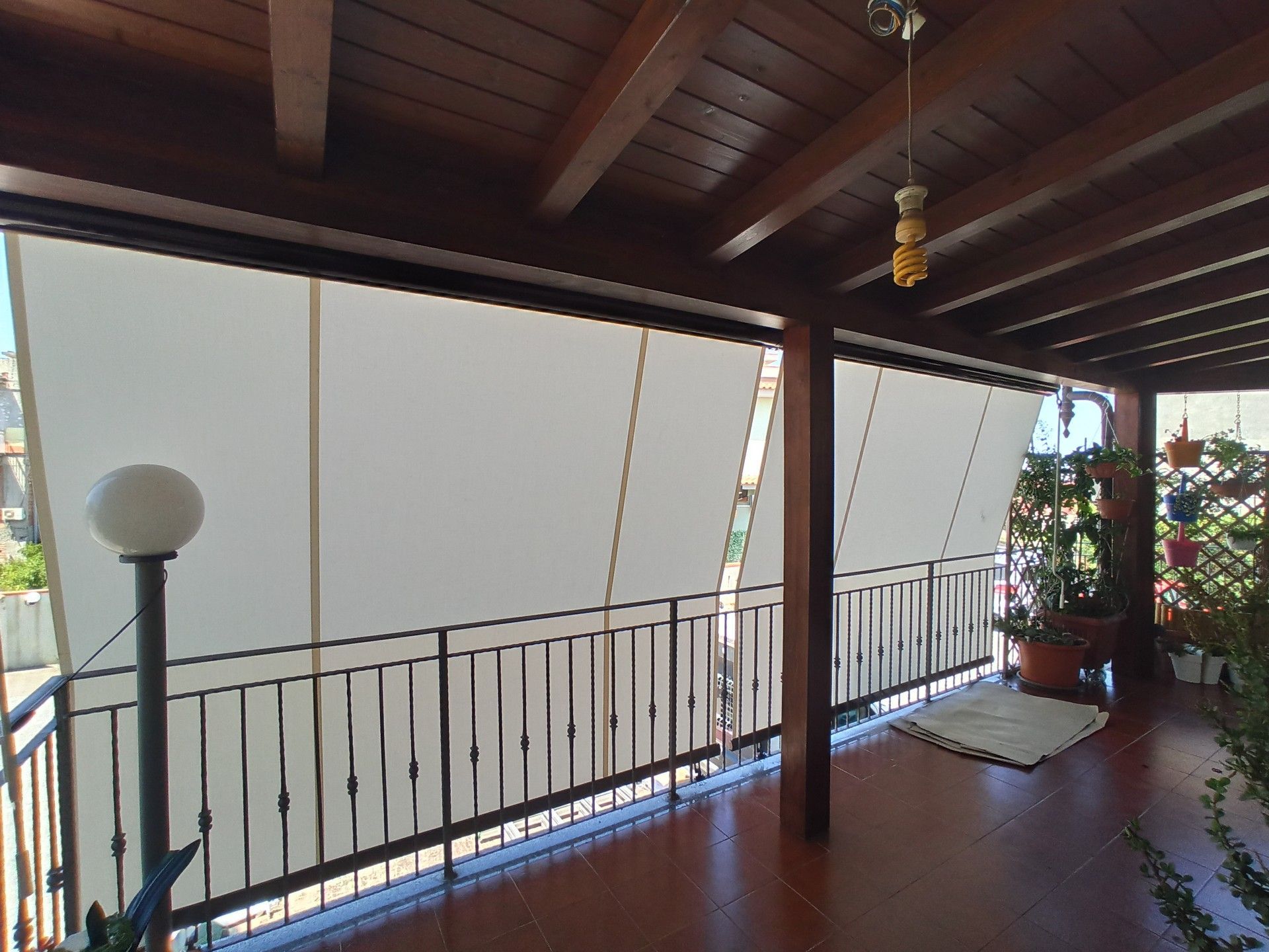 Un balcone con ringhiera in legno e tende da sole bianche