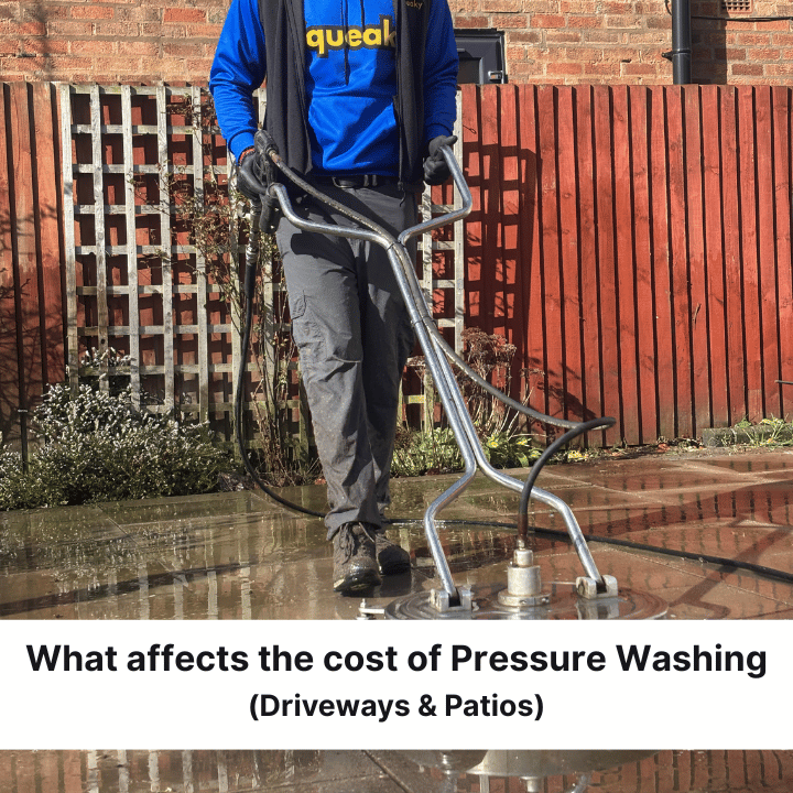 A worker uses a circular surface cleaner to pressure wash a patio in front of a wooden fence.
