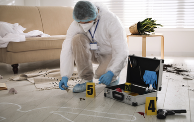 Two people in protective suits are cleaning a dirty floor.