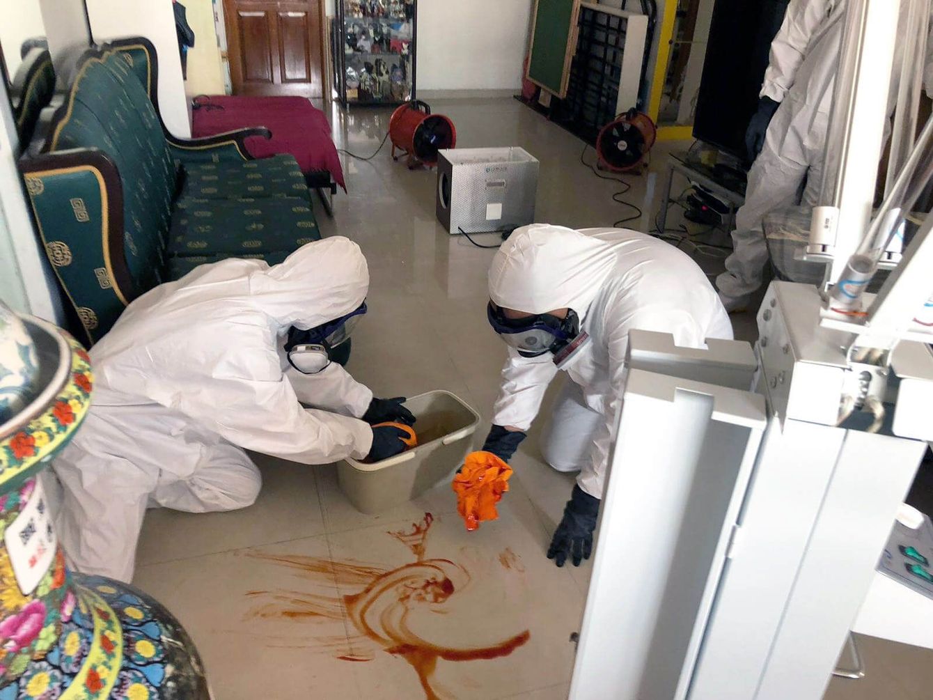 A group of people in protective suits are cleaning a floor.
