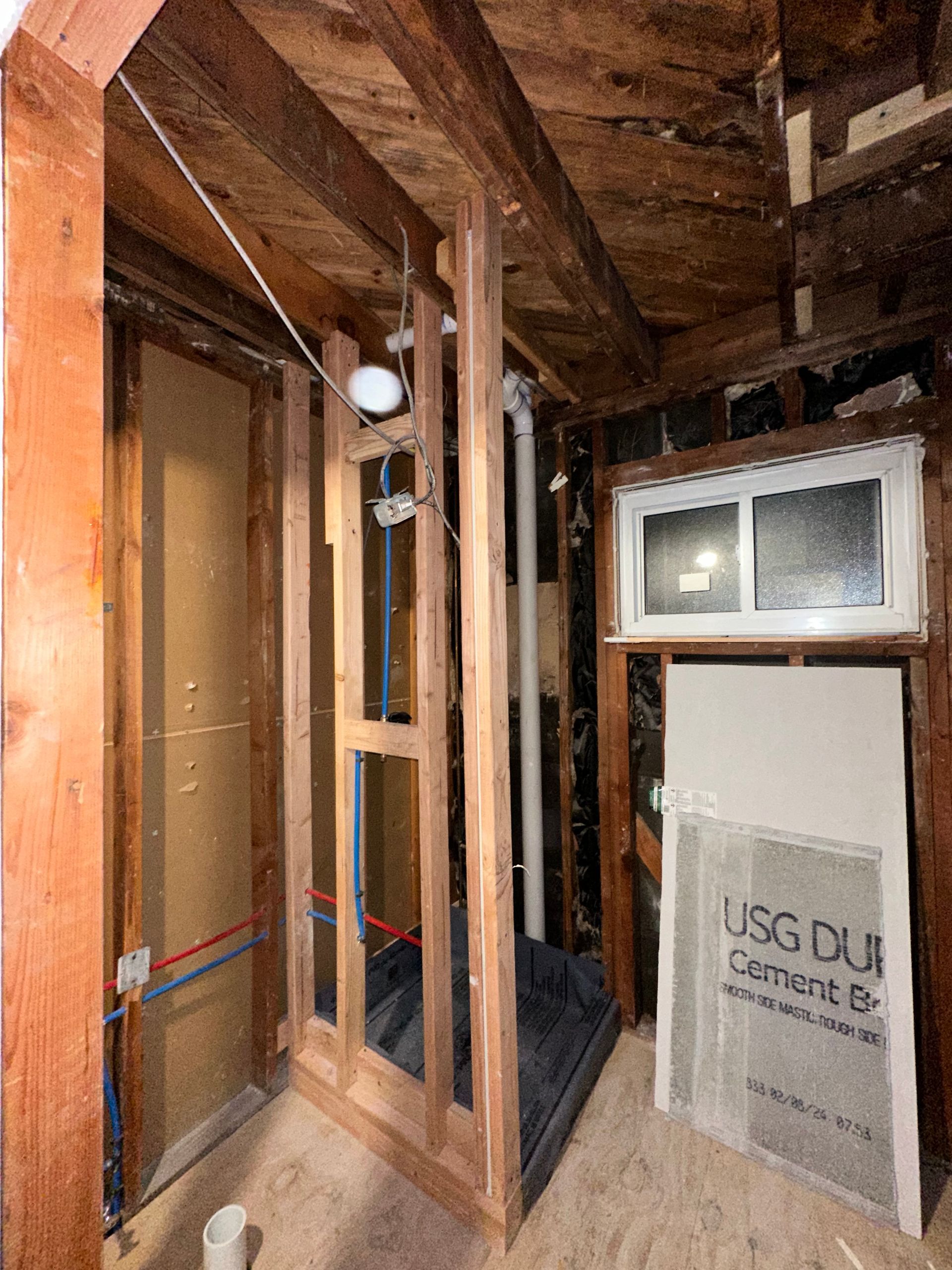 A bathroom under construction with wooden walls and a window.