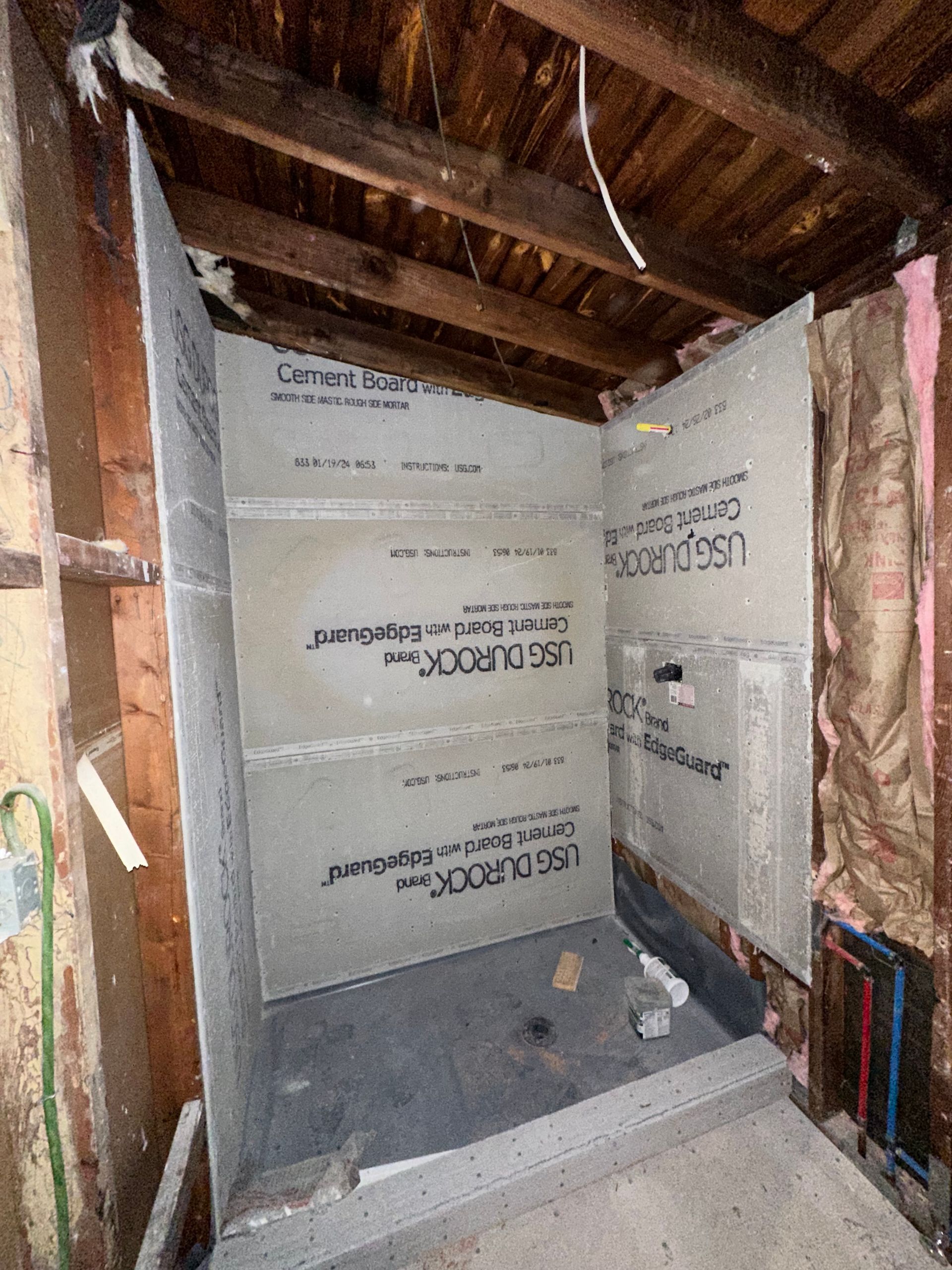 A bathroom under construction with a shower stall and a ceiling.