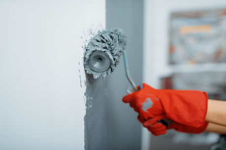 A person is painting a wall with a paint roller.