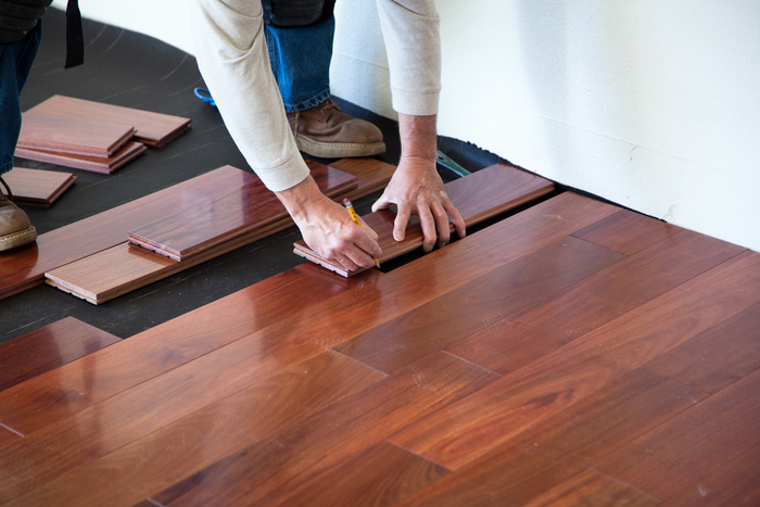 A person is installing a wooden floor in a room.