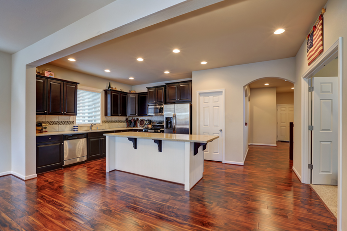 A kitchen with a large island in the middle and hardwood floors.