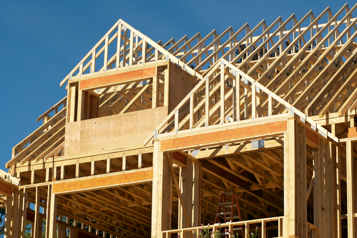 A large wooden house is being built with a blue sky in the background.