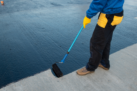 A man is painting a road with a roller.