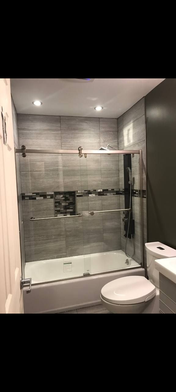 A bathroom with a tub , toilet , sink and shower.