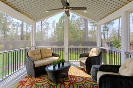 A screened in porch with furniture and a ceiling fan.