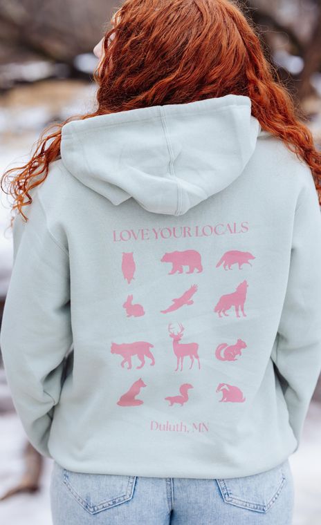 The back of a woman wearing a hoodie with pink animals on it.