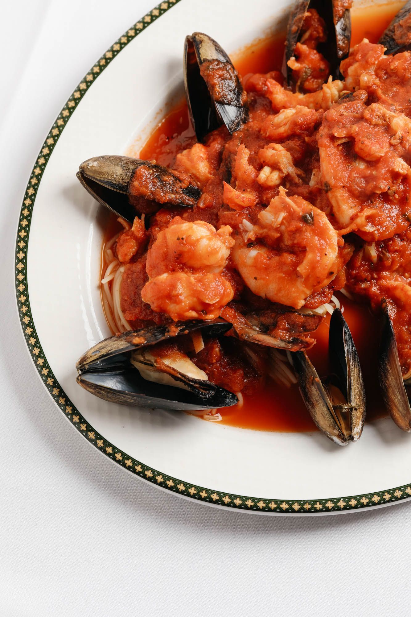A white plate topped with mussels and shrimp in a sauce