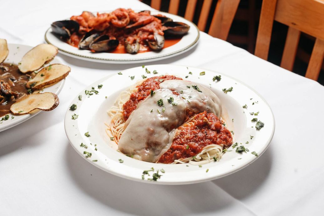 A plate of spaghetti with meatballs and sauce on a table with other plates of food.
