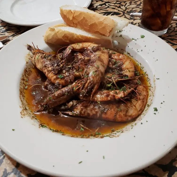 A white plate topped with shrimp and a loaf of bread