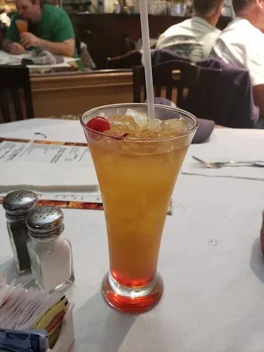 A drink in a tall glass with a straw on a table