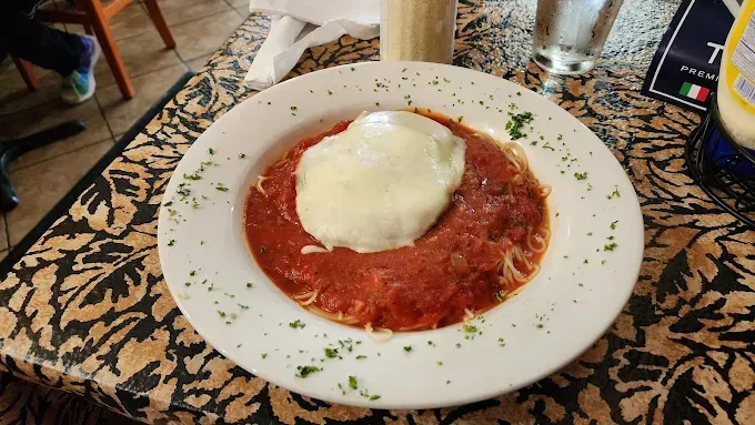 A plate of food with sauce and cheese on a table.