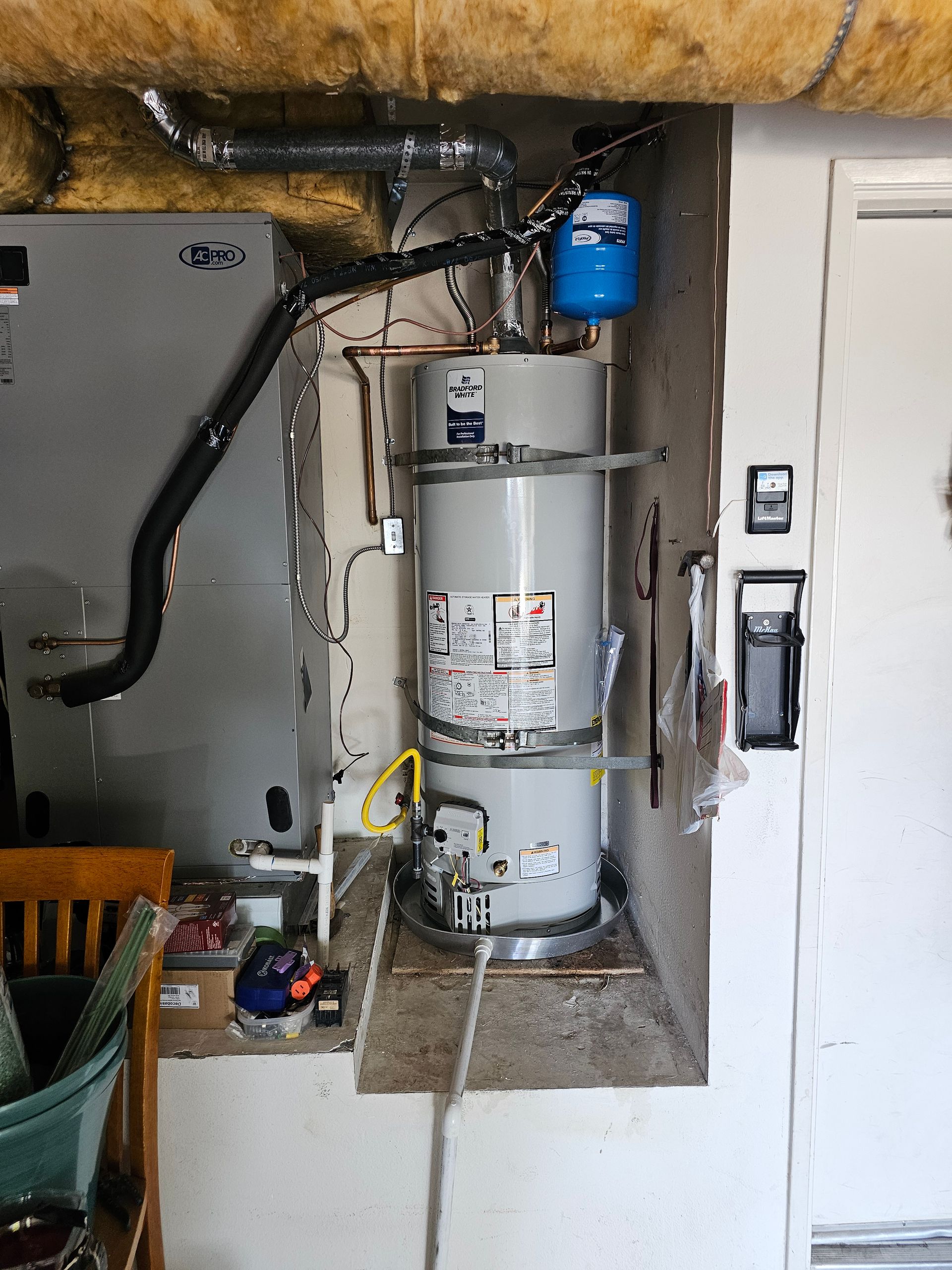 A water heater is sitting in a corner of a room next to an air conditioner.