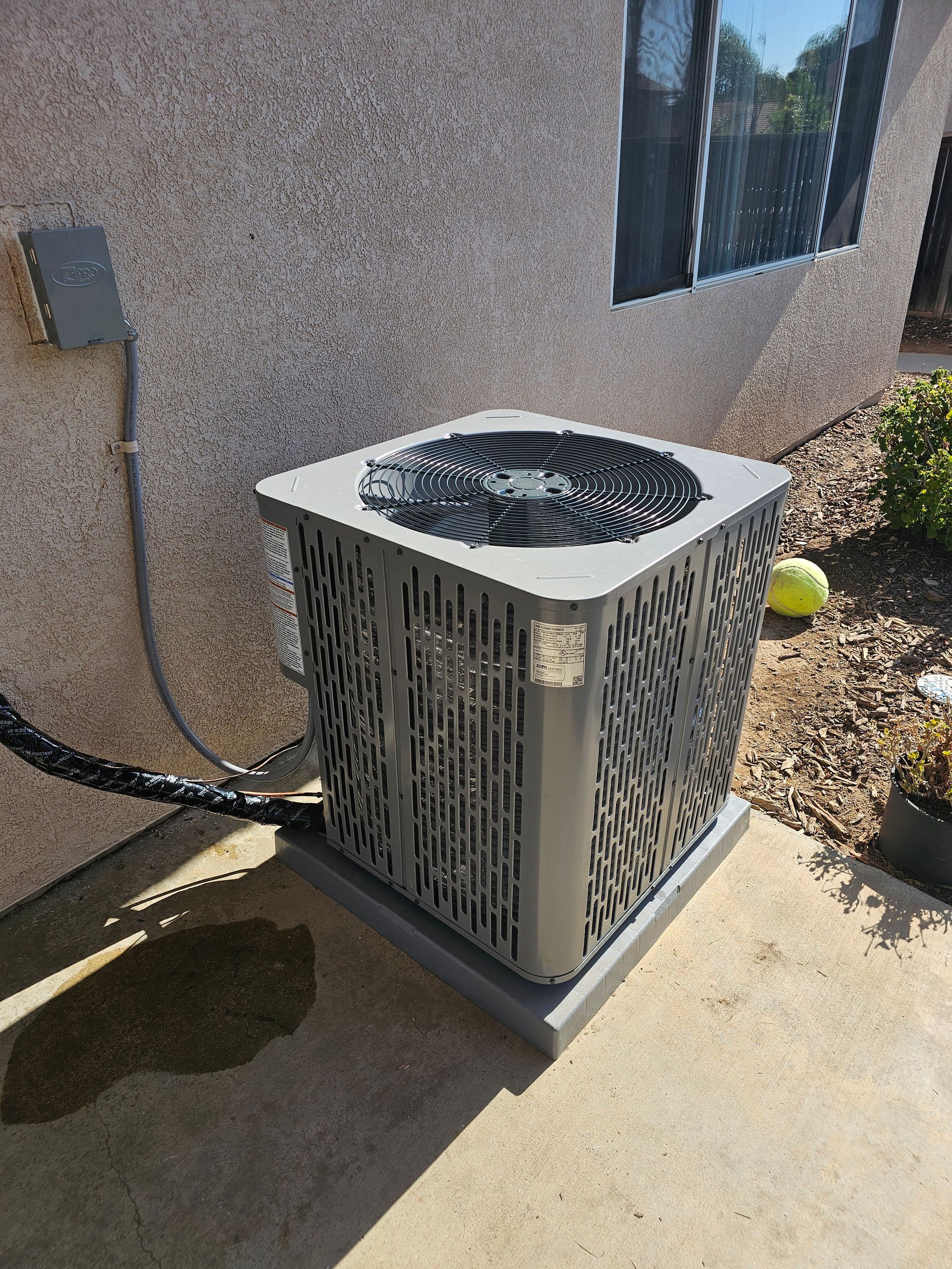 An air conditioner is sitting on the side of a building next to a window.