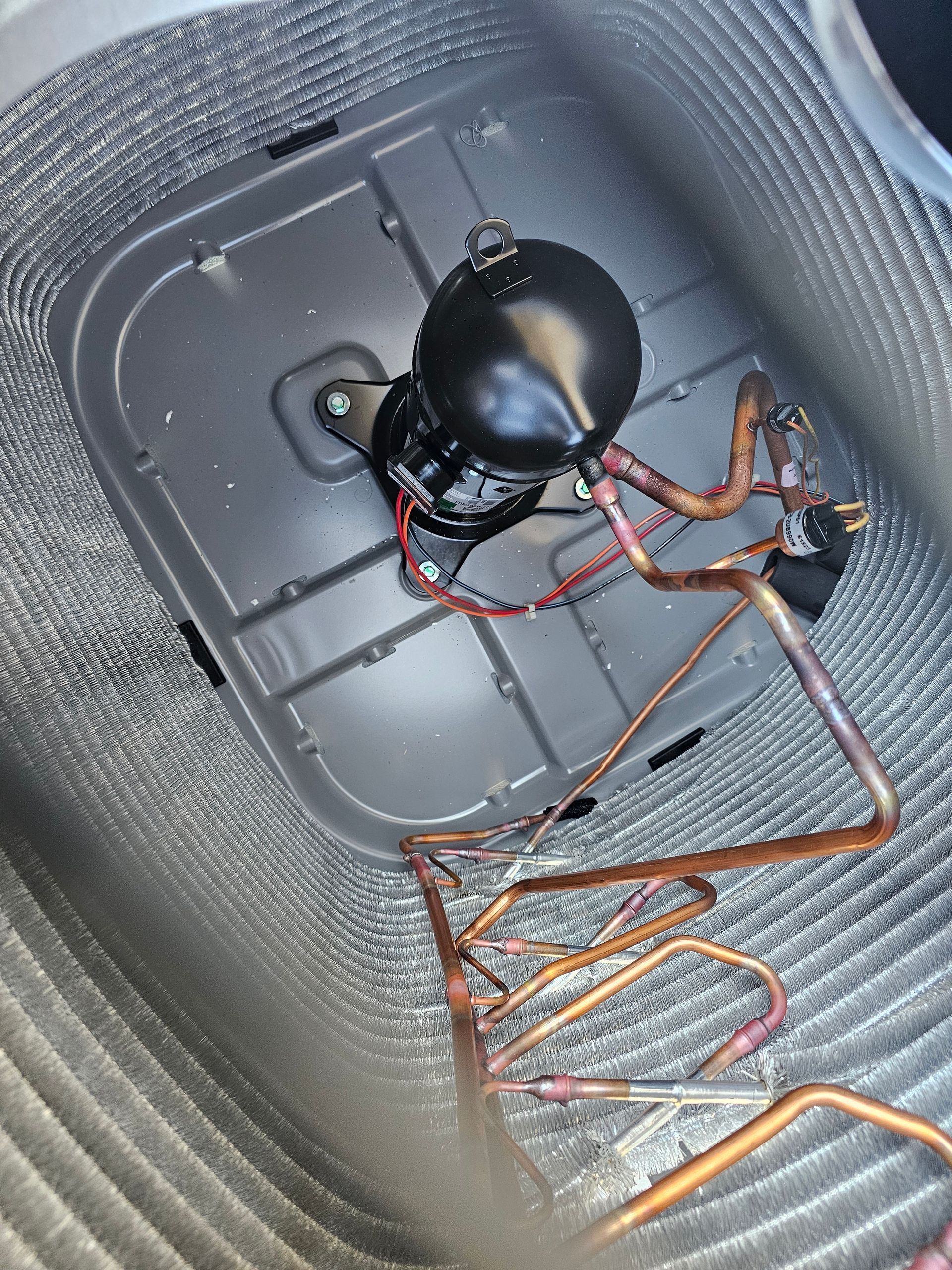The inside of an air conditioner with a compressor and copper pipes
