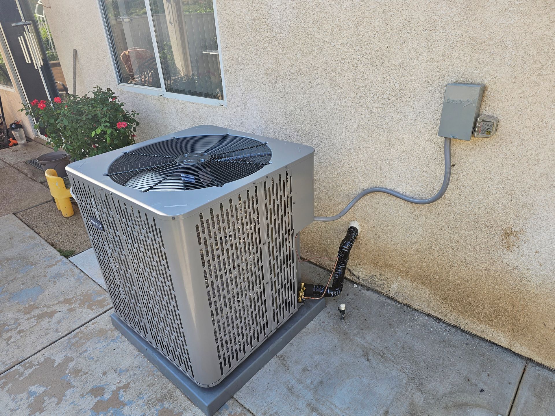 An air conditioner is sitting on the side of a building next to a window.