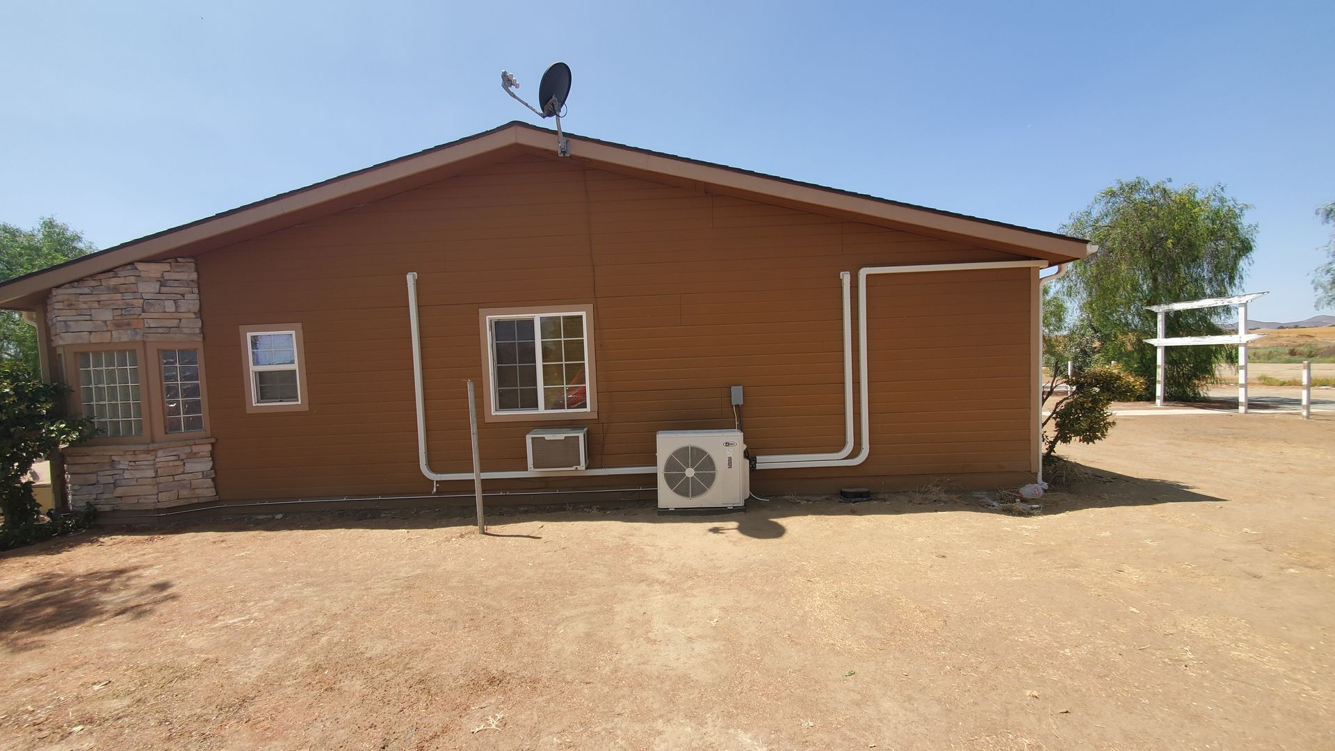 A brown house with a satellite dish on top of it.