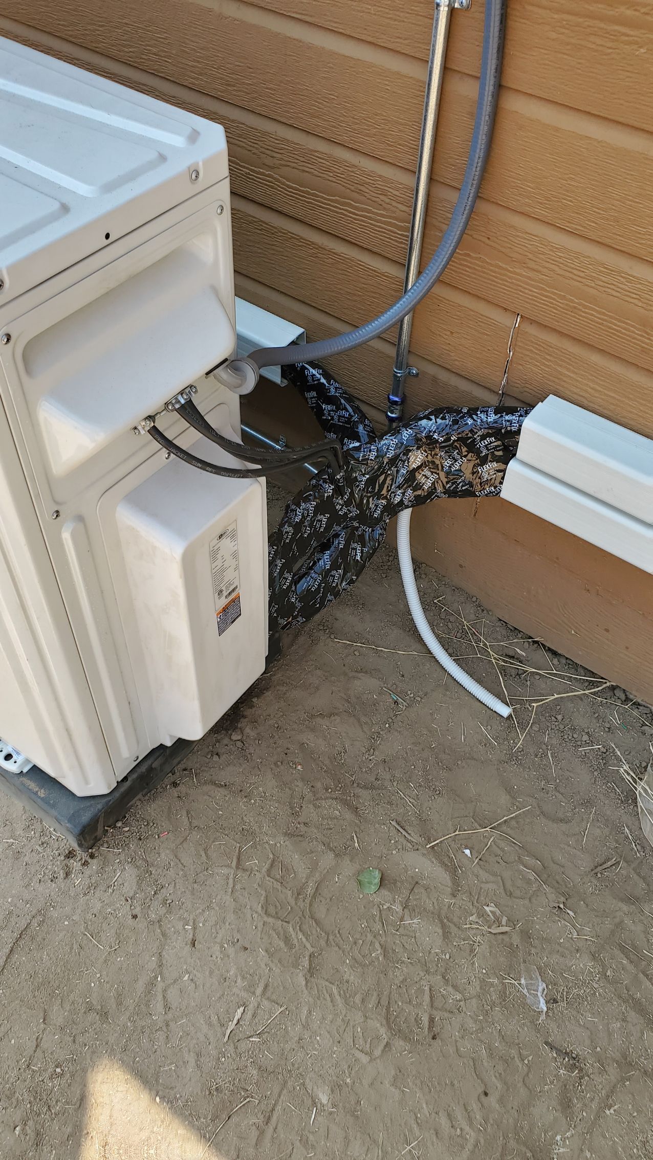 A white air conditioner is sitting on the ground next to a wall.