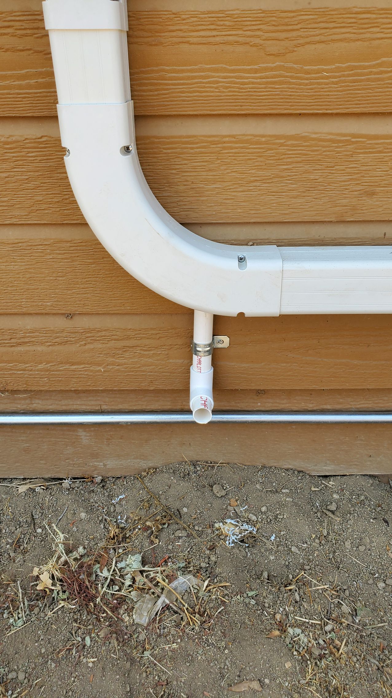A white pipe is attached to a wooden wall.