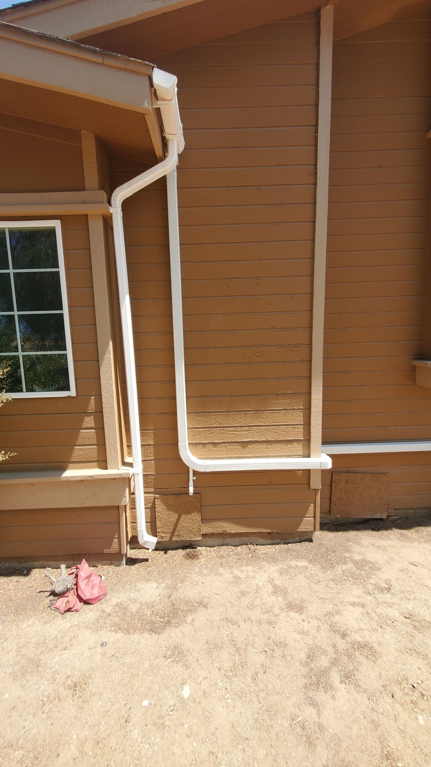 A house with a gutter on the side of it and a window.