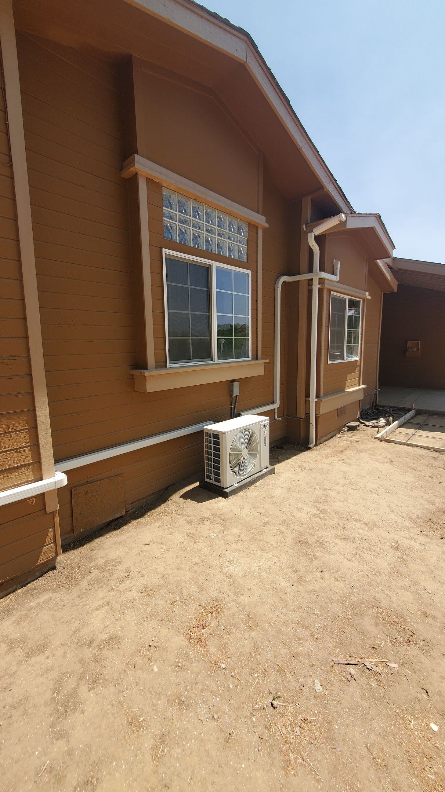 A brown house with a white air conditioner on the side of it.