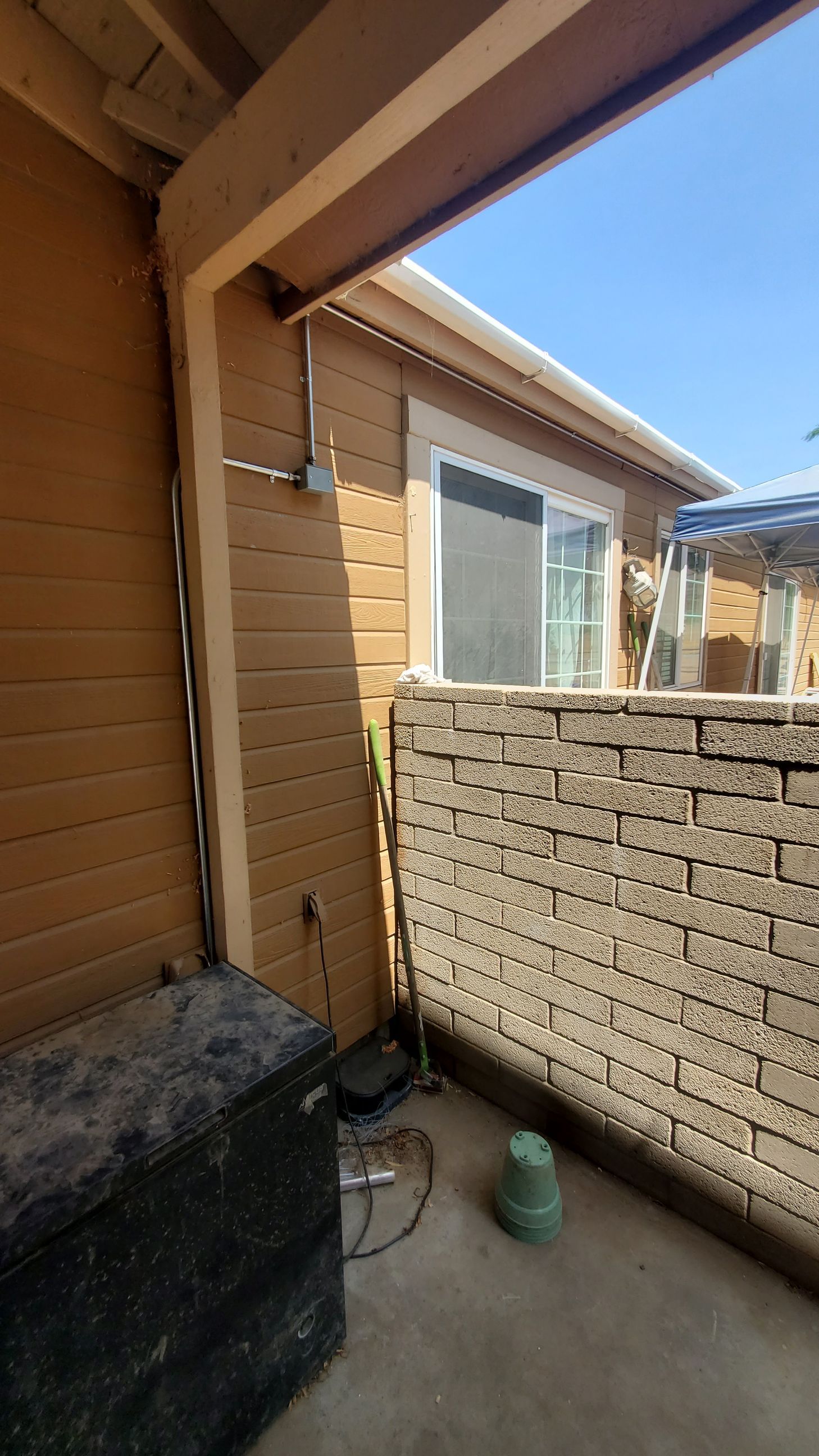 A balcony with a brick wall and a sliding glass door.