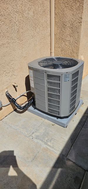 A large air conditioner is sitting on a patio next to a window.