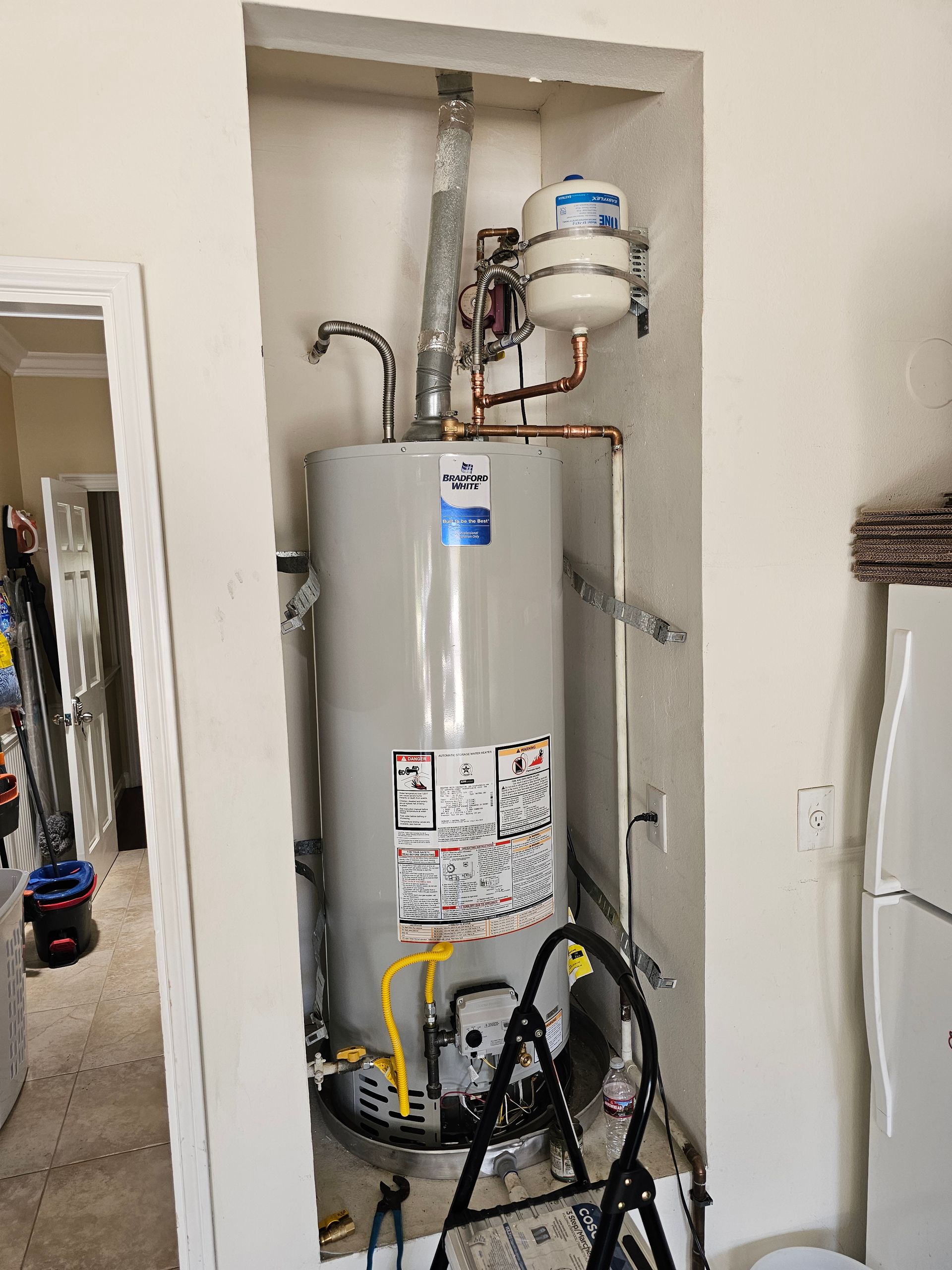 A code compliant water heater installation with drain pan, sediment trap, expansion tank, and more.
