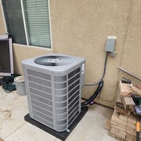 A large air conditioner is sitting on a patio next to a window.