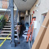 A ladder is sitting on the side of a building next to stairs.
