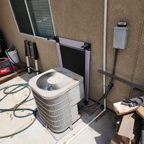 An air conditioner is sitting on the side of a building next to a window.