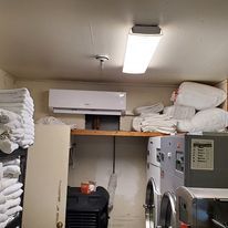 A laundry room with a washing machine , dryer , and air conditioner.