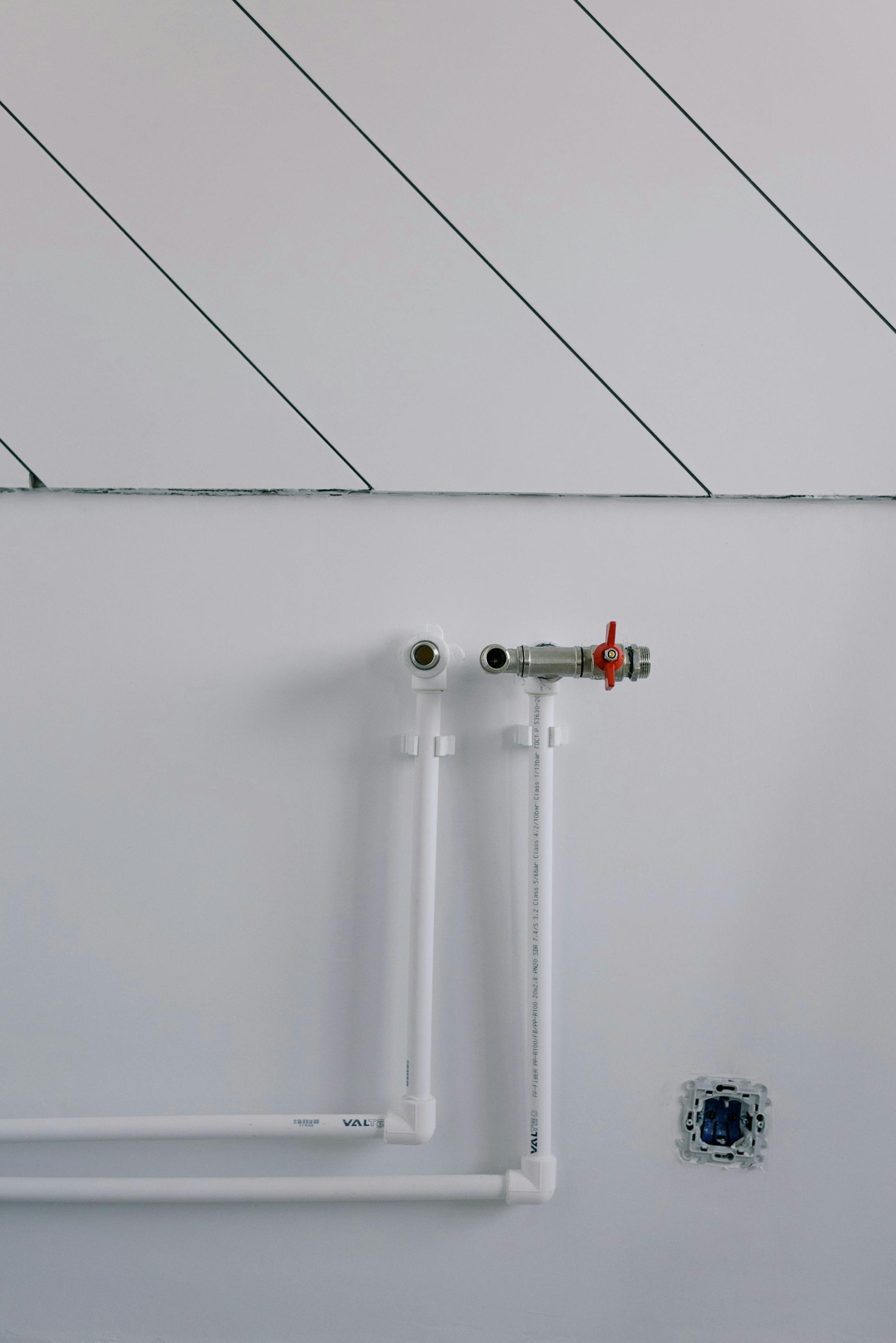 A close up of a white pipe on a white wall.