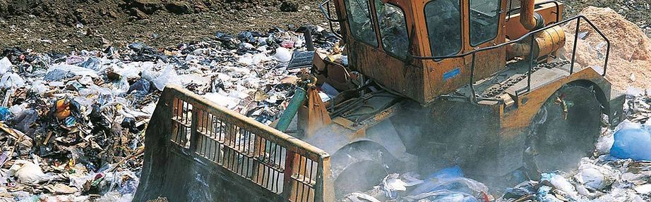 A bulldozer is driving through a pile of trash.