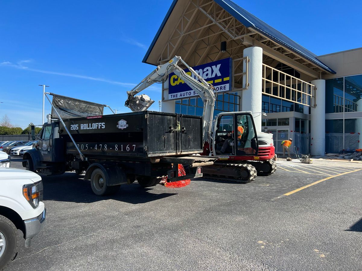 A dump truck and excavator are parked in front of a building.