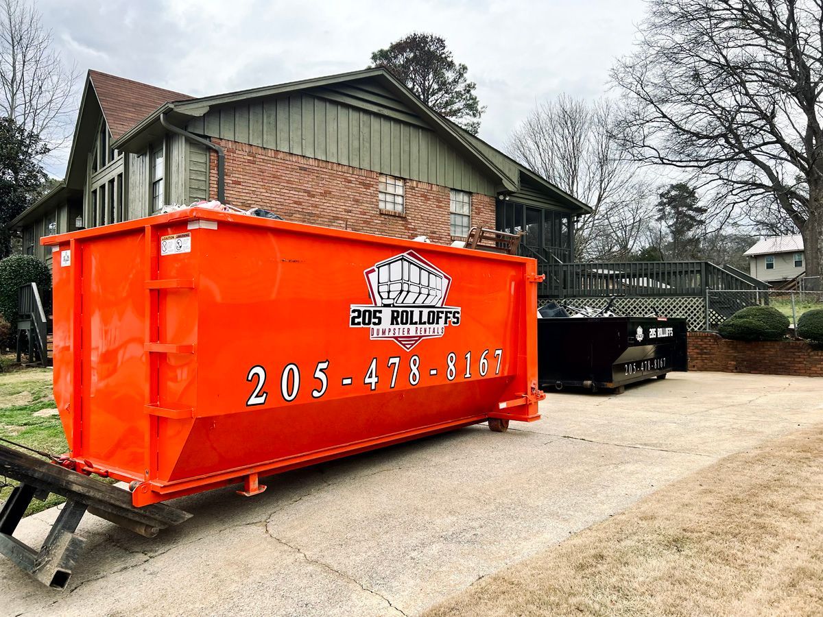 A large orange dumpster is parked in front of a house.